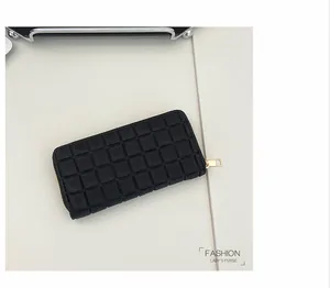 Close-up of black quilted long wallet for women with golden zipper and checkered pattern