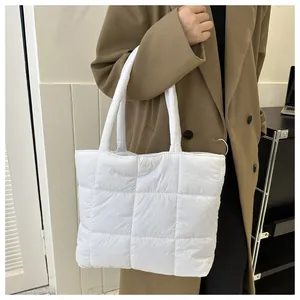 Modern white quilted puffer tote bag shown on a model wearing a classic khaki trench coat