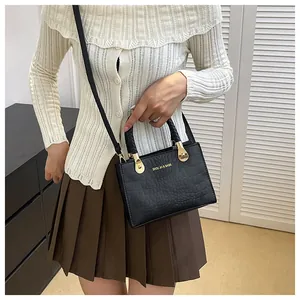 Detail of black faux leather square bag with crocodile pattern and woven handle
