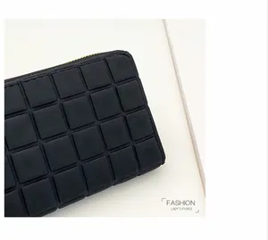 Detail of black matte leather long wallet with embossed grid pattern and gold zipper