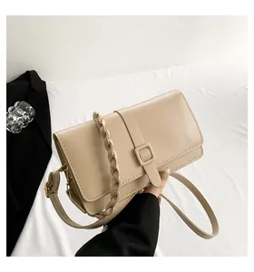 Dettaglio borsa rettangolare beige con manico intrecciato e fibbia decorativa