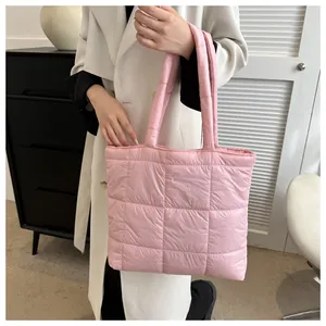 Macro detail of pink quilted down shoulder bag featuring soft texture and square stitching