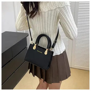 Detailed view of a black lychee texture crossbody bag with woven handles on a model