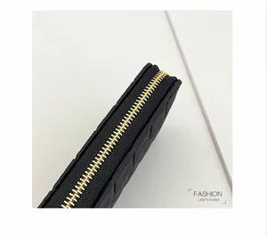 Detailed close-up of golden metal zipper and quilted leather on black long purse