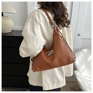 Detail view of a brown faux leather hobo bag with a stylish silver chain and star logo