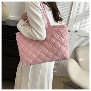 Pink quilted tote bag with diamond stitching shown on a model in a minimalist setting