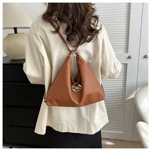 Caramel brown triangle leather backpack shown on shoulder to illustrate size and fit on a model