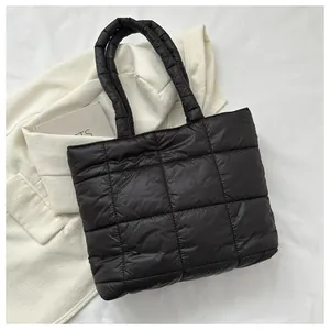 Detail of black quilted down tote bag showing puffy square stitching and padded nylon handle