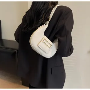 Detail shot of white crescent bag featuring a rectangular gold metal buckle closure