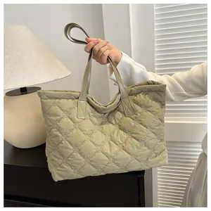 Detail of sage green quilted tote bag featuring classic diamond stitching and dual handles