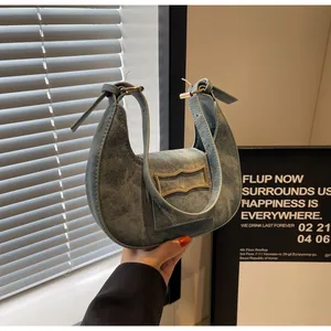 Detail showing vintage denim hobo bag fabric with metallic buckle and washed texture