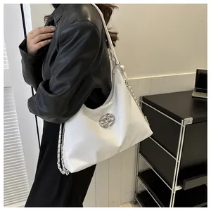 Detailed shot of white PU leather shoulder bag featuring silver metal logo and chain strap