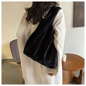 Vue détaillée d'un grand sac cabas noir en fausse fourrure porté avec un manteau beige d'automne