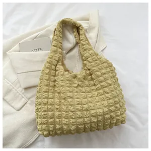 Macro view of textured yellow popcorn fabric on a minimalist puff shoulder handbag