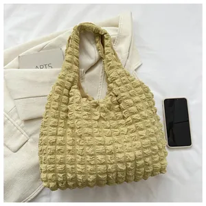 Detailed macro of creamy yellow puff textured shoulder bag with 3D bubble fabric effect