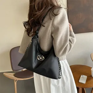 Fashionable black crescent shoulder bag with chain strap shown on a model in a cafe