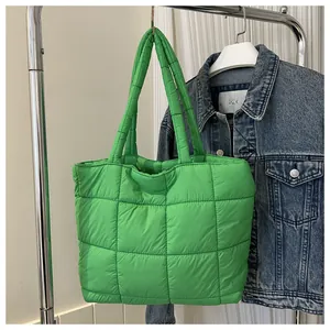 Detail of green quilted down tote bag featuring large grid stitching and soft texture