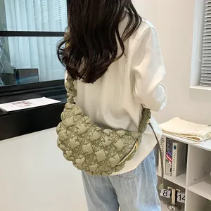 Quilted light green puffer cloud bag with golden zipper shown on a shoulder