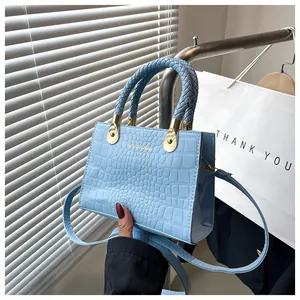 Detail of light blue crocodile embossed leather mini bag with braided top handle