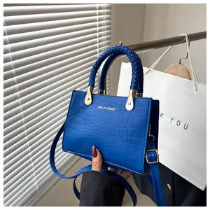 Close-up of klein blue crocodile-embossed faux leather bag with woven handle details