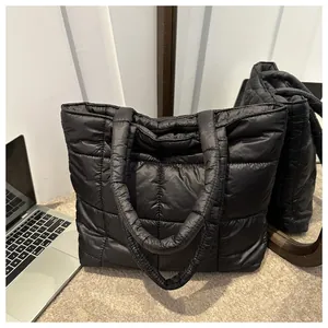 Detail of black quilted puffer tote bag with square stitching on beige carpet