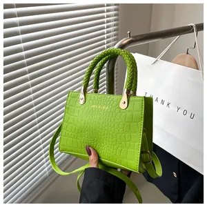 Detail of bright green crocodile texture handbag with woven handle and gold hardware