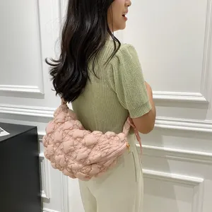 Detail of light pink puff quilted shoulder bag shown on model with soft fabric texture