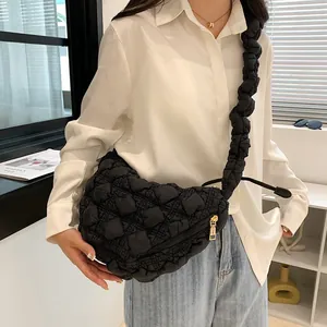 Detail of black cloud puffer bag with quilted texture and golden zipper on shoulder strap