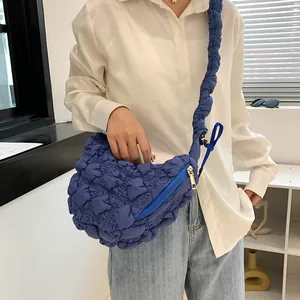 Detailed view of dark blue bubble textured puffy cloud bag with gold zipper and strap