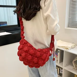 Detail of red bubble quilted shoulder bag with matching pleated strap and gold zipper