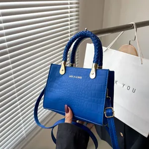 Klein blue crocodile pattern crossbody bag with a woven handle and gold hardware detail