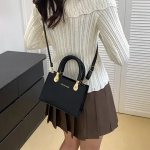Fashionable black crocodile embossed crossbody bag with woven handle and gold accents
