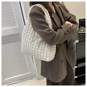 Close-up of white bubble texture shoulder bag styled with a brown winter coat