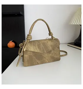 Close-up of vintage khaki textured messenger bag with unique knotted handle and gold hardware