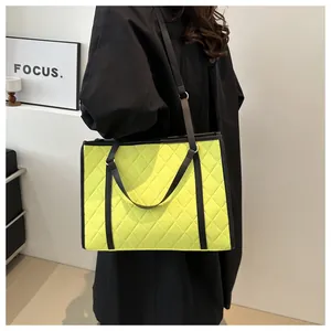 Detail of neon green quilted tote bag with classic rhombus pattern and black shoulder straps
