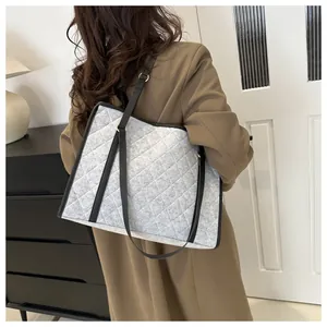 Detailed shot of grey quilted felt tote bag with black straps worn over the shoulder