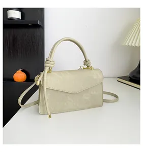 Detail of matte leather handbag with knotted handle and envelope flap design