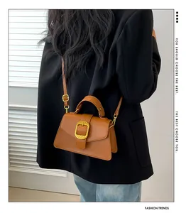 Brown leather satchel with gold buckle detail worn by model in black blazer and jeans