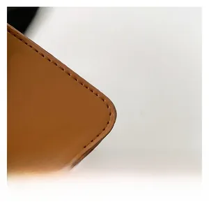 Detail view of the brown leather texture and precise stitching on the fashion bag