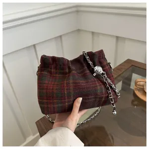 Detail of tartan wool bucket bag featuring silver chain strap and metal ball clasp