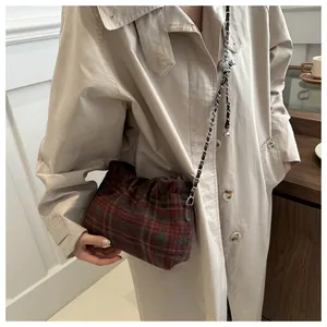 Detail of red and green plaid woolen bucket bag with drawstring and silver chain strap