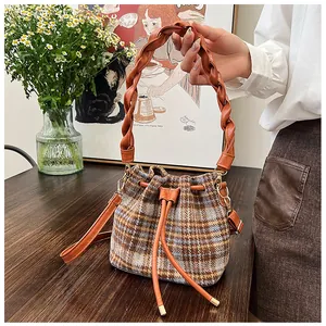 Detail of checkered wool bucket bag with woven handle and drawstring closure