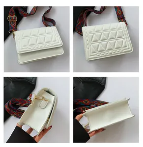 Detail of white quilted square bag showing geometric stitching and wide colorful strap