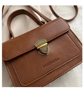 Detail of a brown vintage leather handbag showing the gold shield-shaped lock and texture
