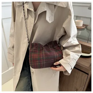 Close-up of wool plaid bucket bag with metallic chain strap and autumn texture detail