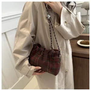 Detail of red and green plaid woolen bucket bag with silver chain strap and metal buckle