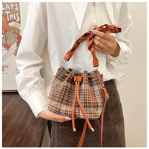 Detail of tartan wool bucket bag with braided handle and brown leather drawstring closure