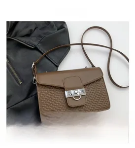 Detail shot of deep brown leather crossbody bag featuring heart-embossed texture and silver ring