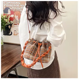 Detail of retro plaid wool bucket bag featuring orange drawstring and woven leather handle