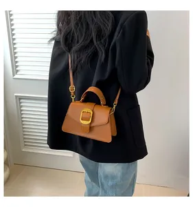 Rear view of model wearing a brown leather handbag with a large gold buckle detail